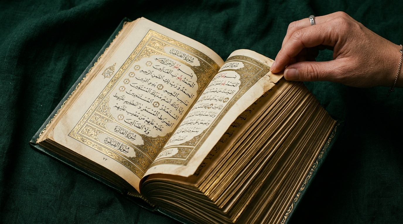 Hand turning the pages of an ornate open Quran on dark green fabric